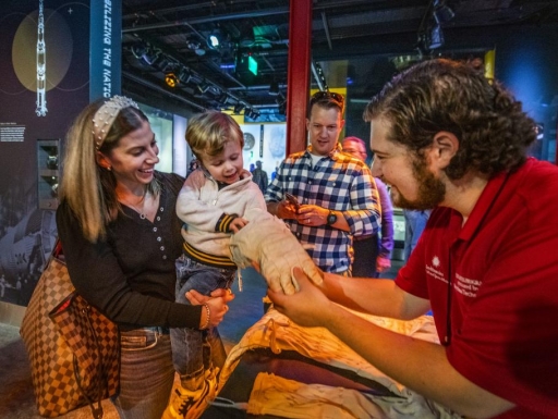 A family looks at examples of astronauts gloves. 