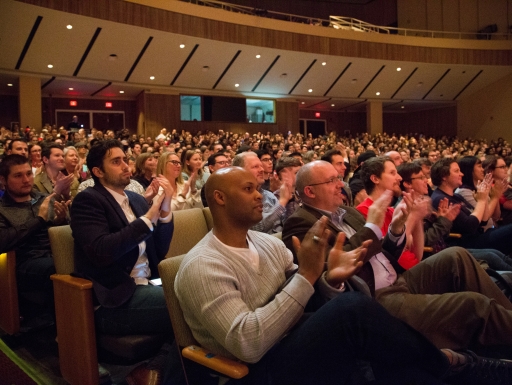 A filled audience applauds a performance