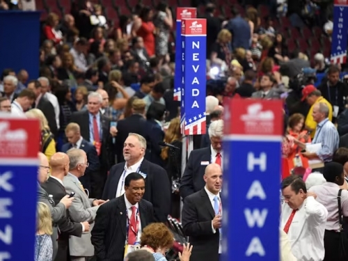 A crowd of people with tall pillars in red, white and blue with state names on them.