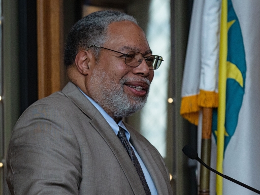 Secretary Bunch at a podium with the Smithsonian flag to his left.