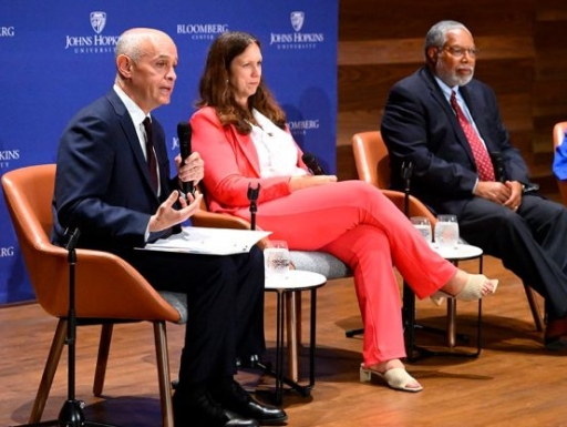 Panelists sit on a stage. 